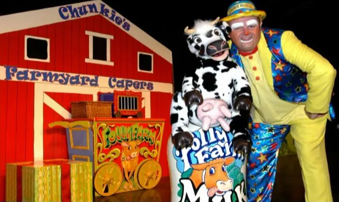 Chunkie in clown costume with a cow mascot on the Chunkie's Farmyard Capers stage