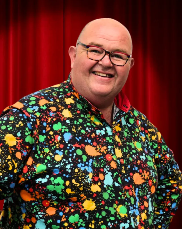 Chunkie Russell, children's entertainer, smiling in a colourful paint-splash shirt