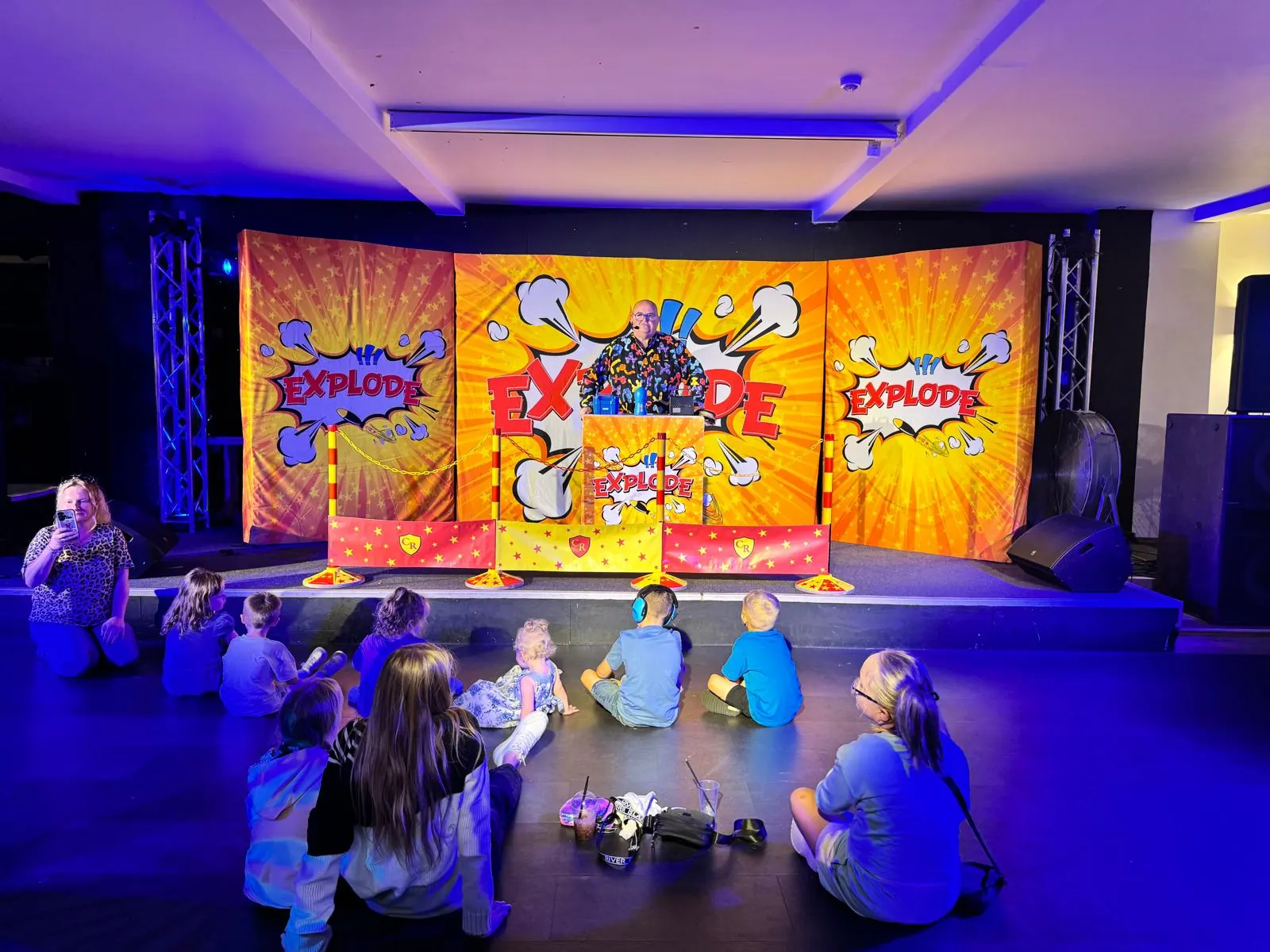 Children sitting in front of a colourful stage at a family show