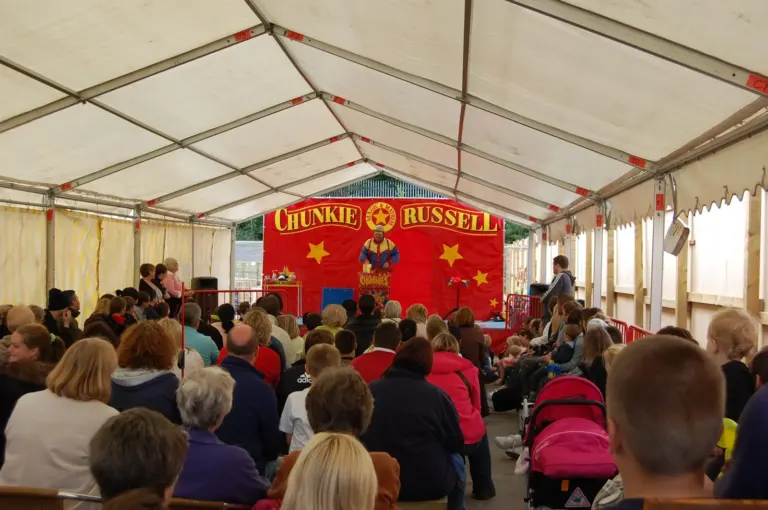Families watching a Chunkie Russell show in a packed marquee